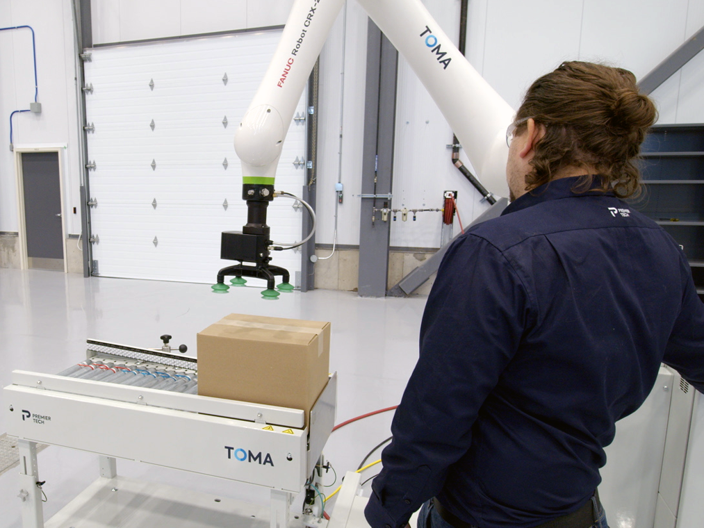 Team member working with the TOMA cobot palletizer